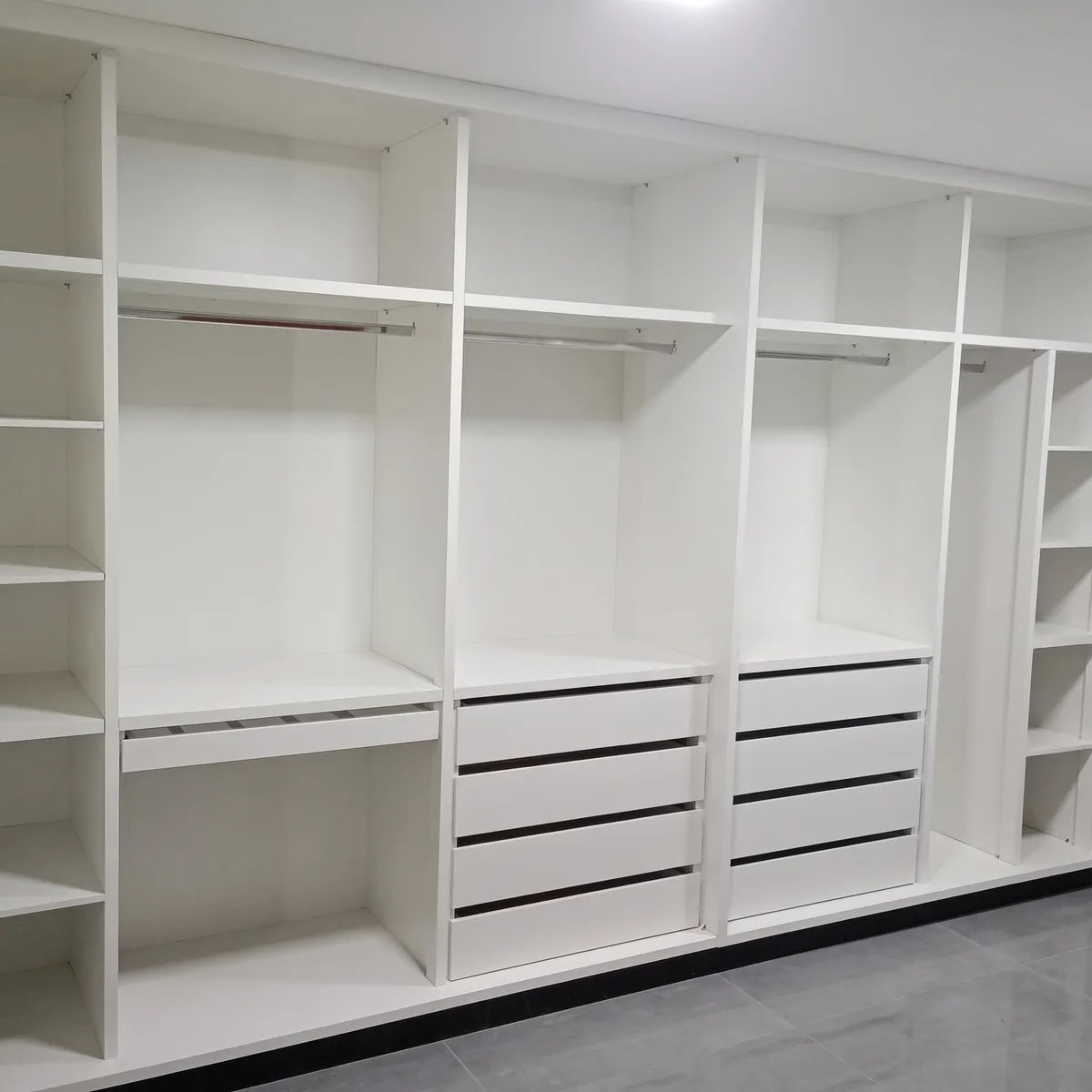 Closet planejado branco com gavetas e cabideiros