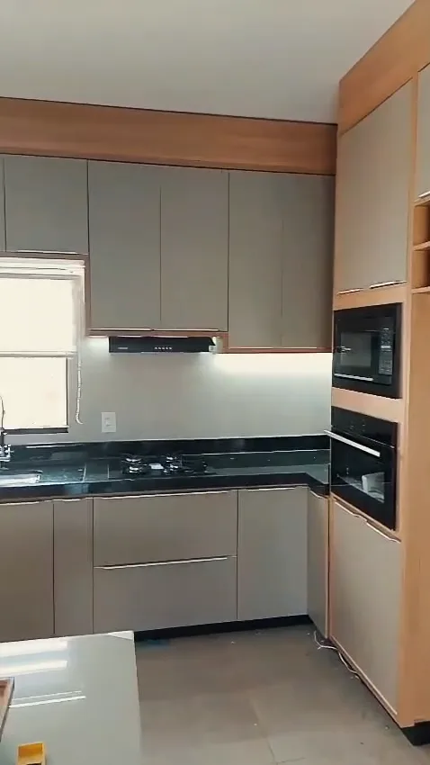 Cozinha planejada pronta, com armários cinza, faixa de madeira, granito preto e torre de madeira com forno e micro-ondas