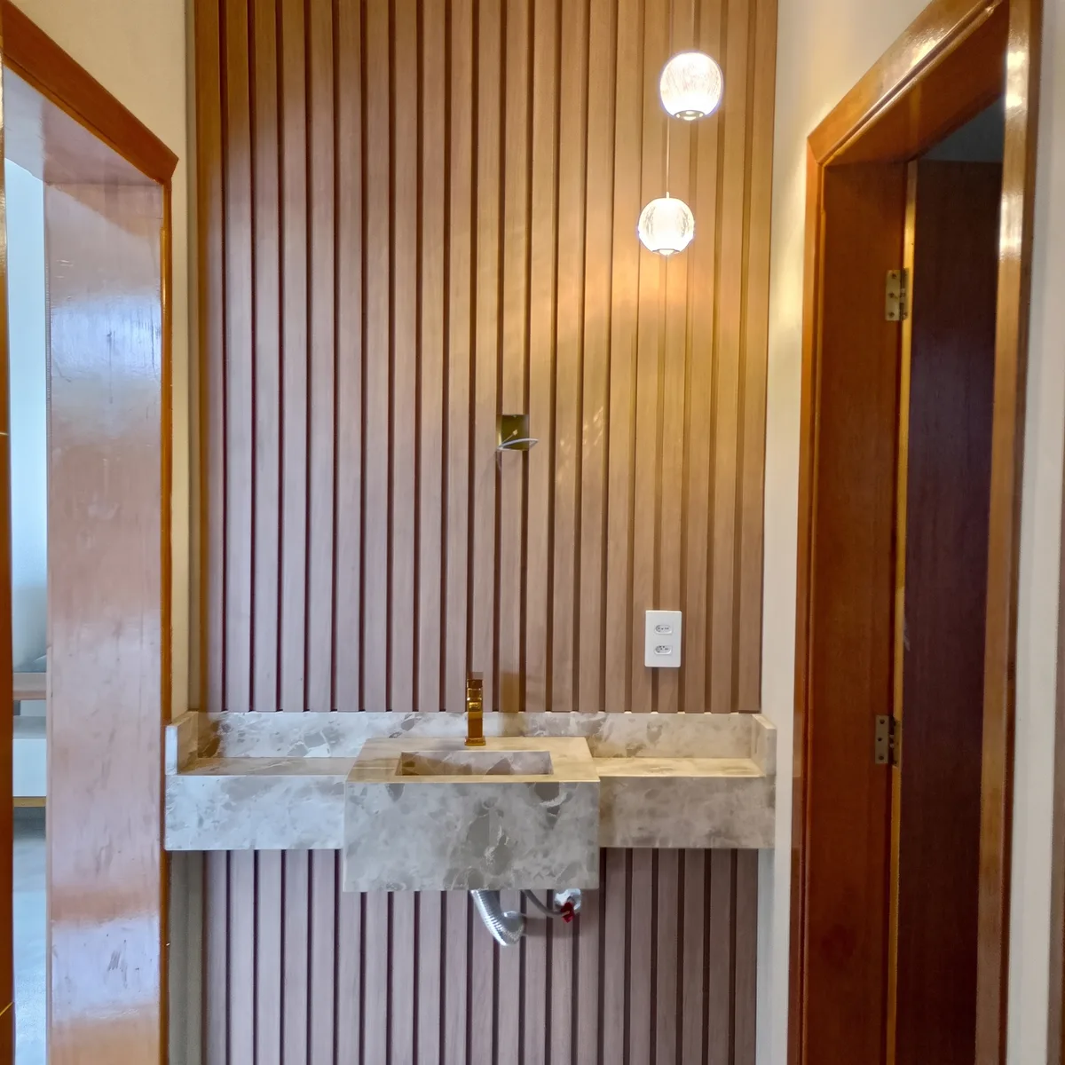 Lavabo com parede ripada amadeirada e bancada de pedra